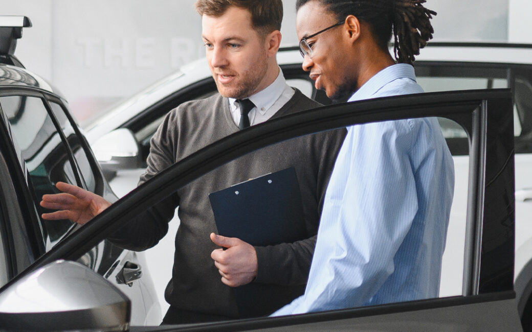 Car salesman shows a man the inside of a vehicle