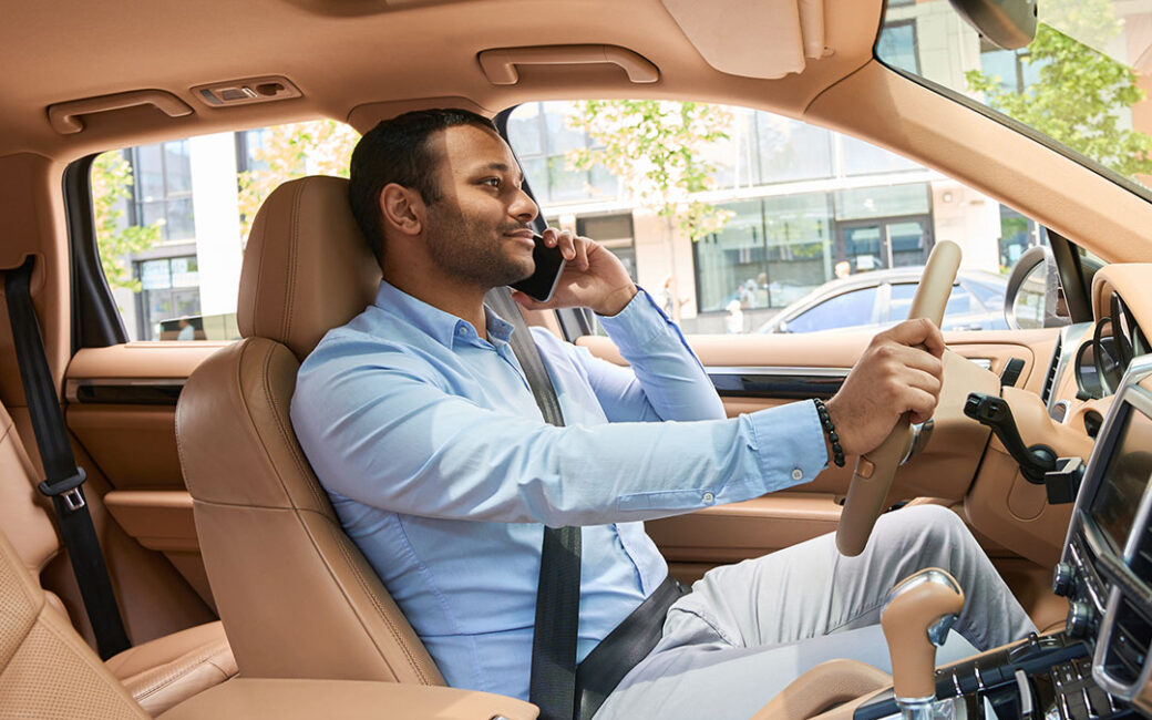 Driver with smartphone in hand driving automobile