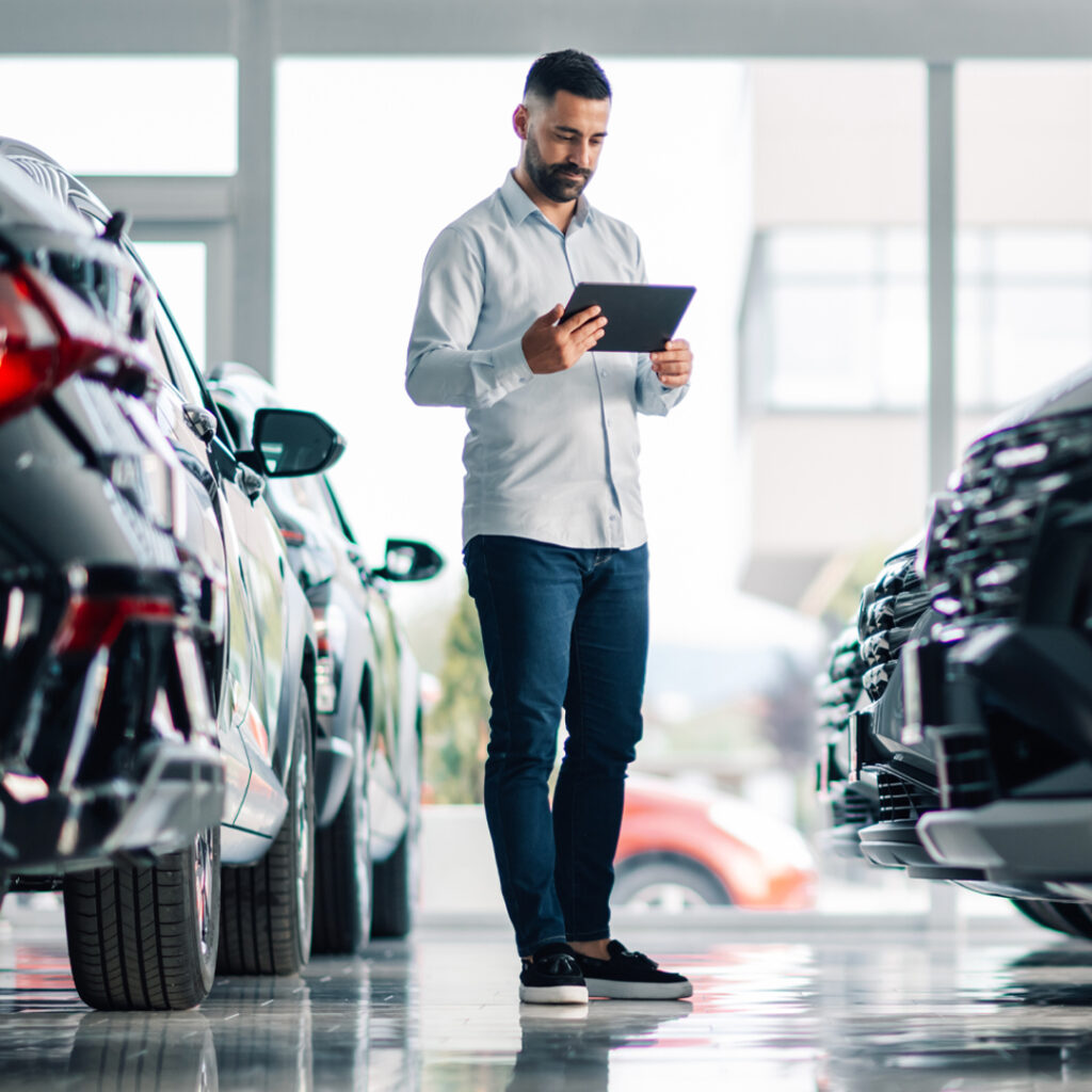 Man on tablet looks at vehicles