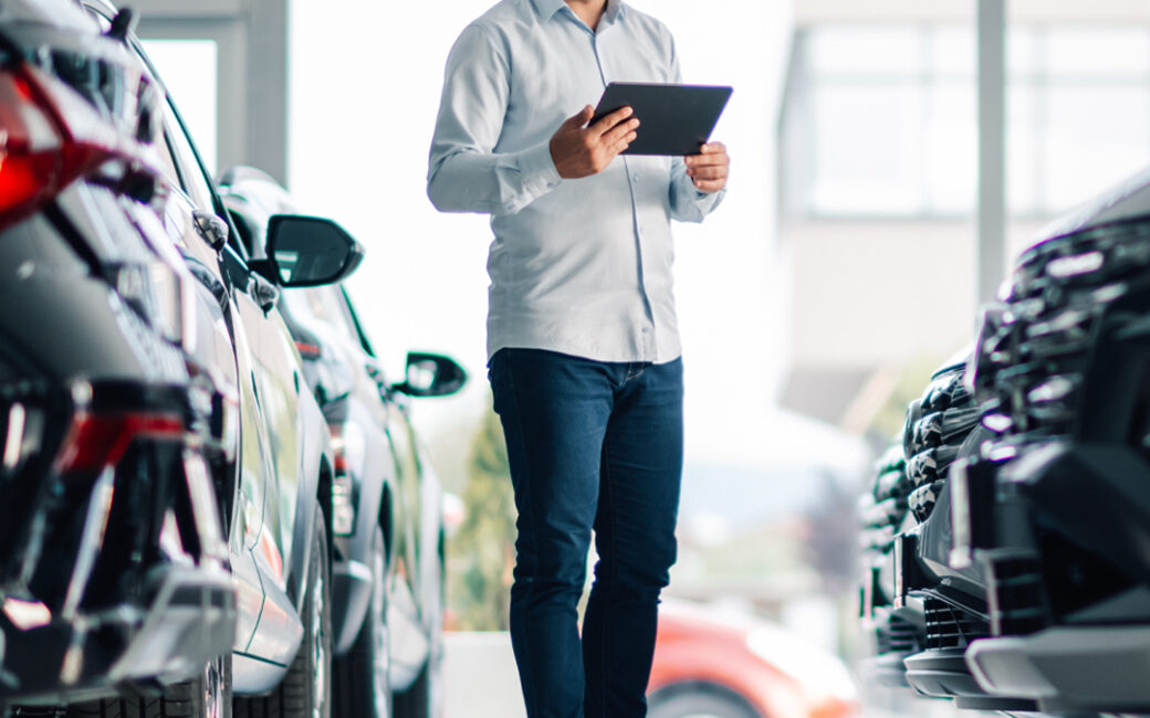 Man on tablet looks at vehicles