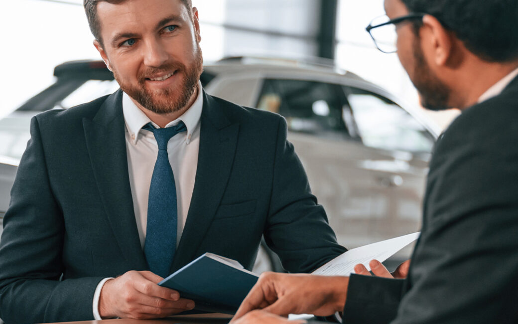 Two businessmen are working together in the car showroom