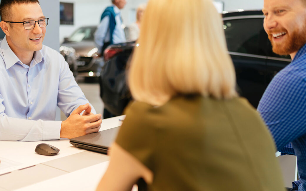 Car salesman talking with customers