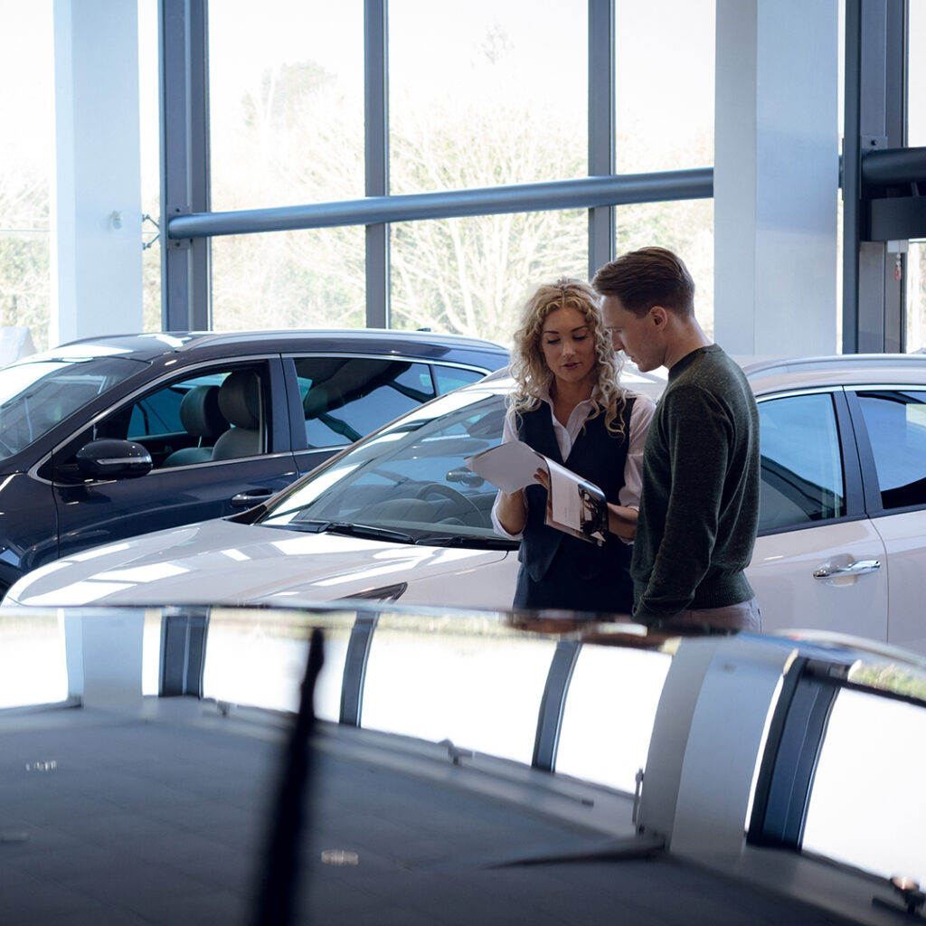 Man and woman look over brochure in car dealership