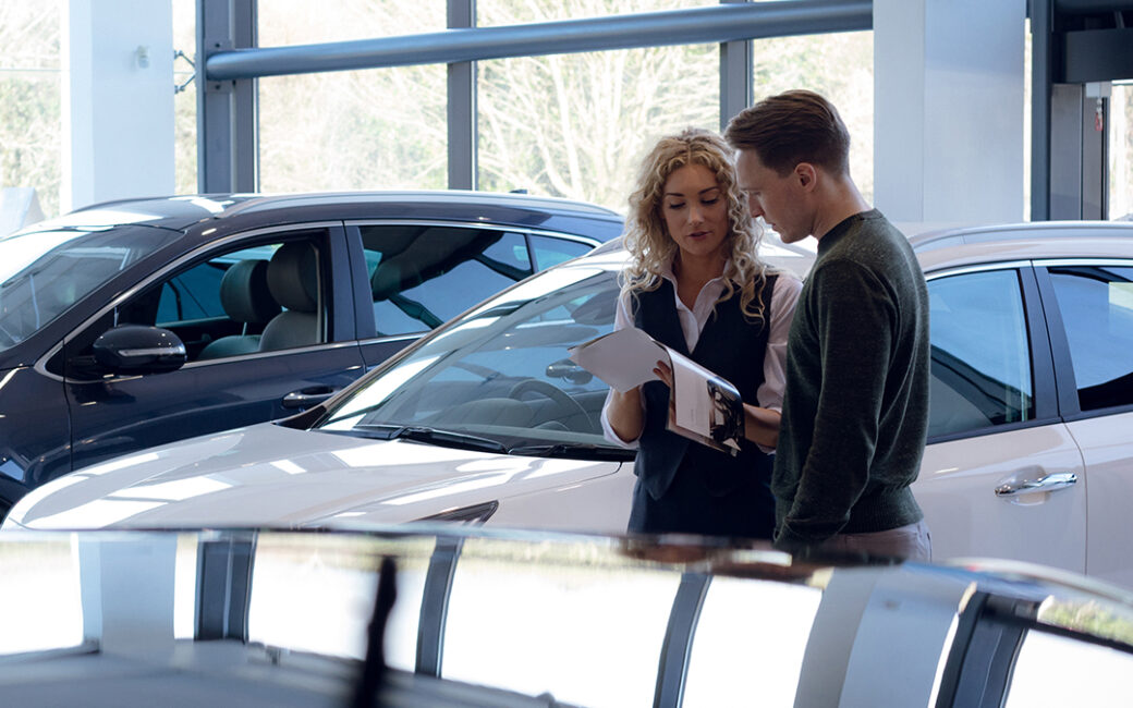 Man and woman look over brochure in car dealership