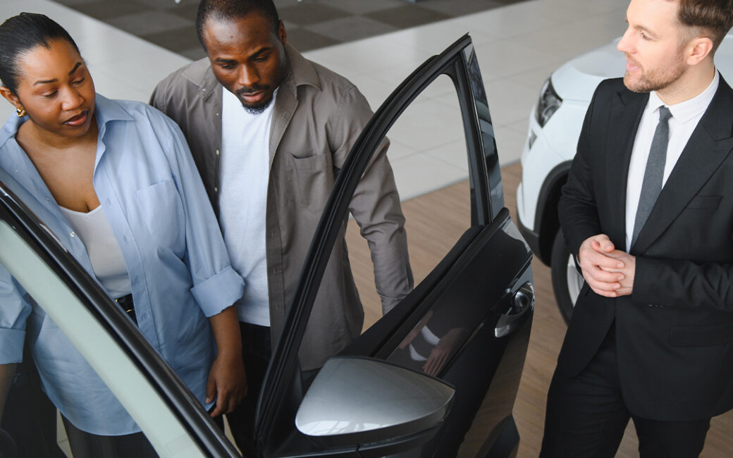 Salesman shows couple a vehicle.