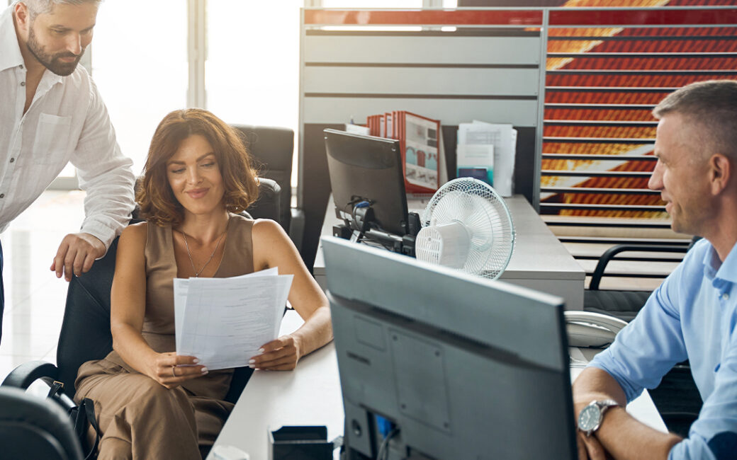 Man and woman look over paperwork at dealership.