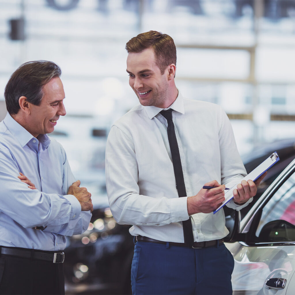 2 car salesman discussing a vehicles info.
