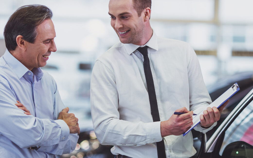 2 car salesman discussing a vehicles info.